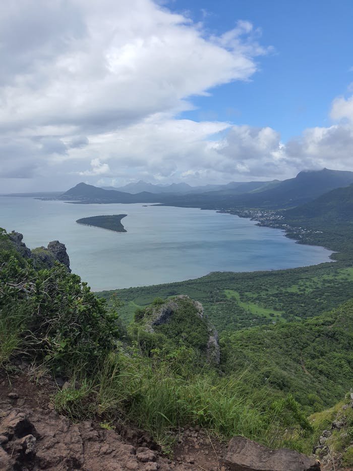 Breathtaking view of a coastal landscape with lush greenery, mountains, and sea under a cloudy sky.